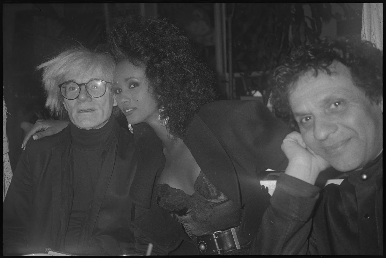 Narozeninová party: Andy Warhol, Iman a Azzedine Alaïa, 1986. Fotografická reprodukce z 35mm negativu Andy Warhola